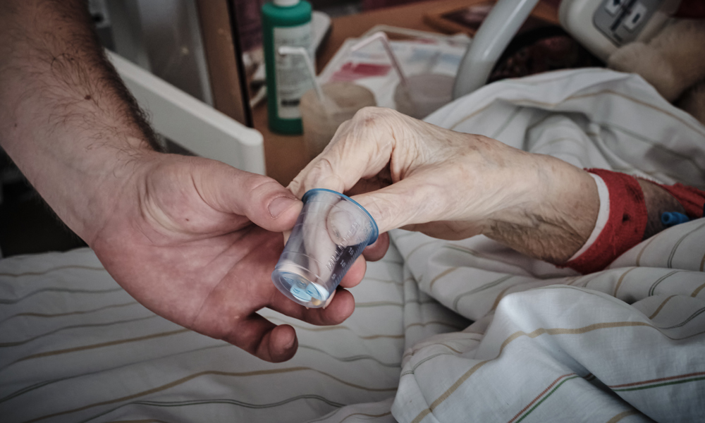 Auf der Alterstraumatologie: Patient nimmt Tabletten von Hand entgegen.