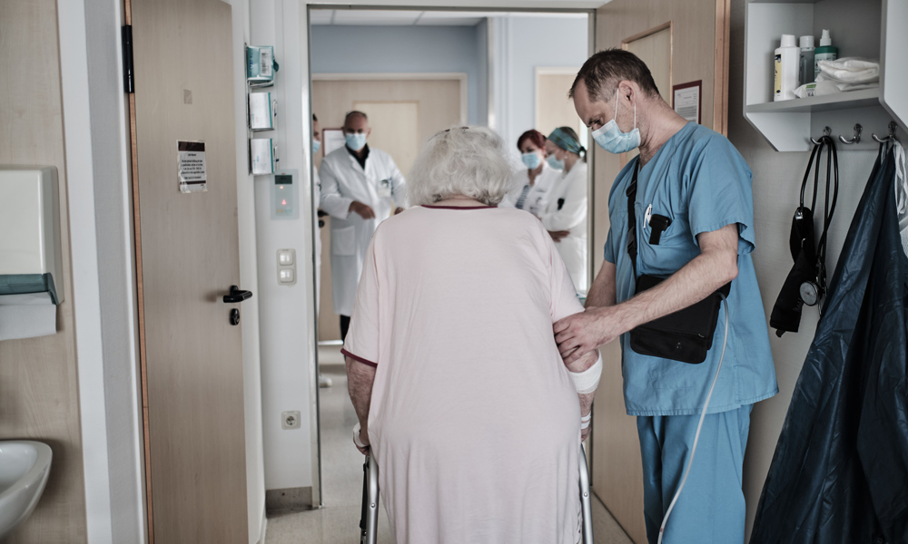 Wieder mobil werden: Ein Pfleger unterstützt eine ältere Patientin.